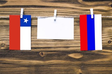 Hanging flags of Chile and Russia attached to rope with clothes pins with copy space on white note...