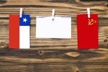 Hanging flags of Chile and Soviet Union attached to rope with clothes pins with copy space on white...