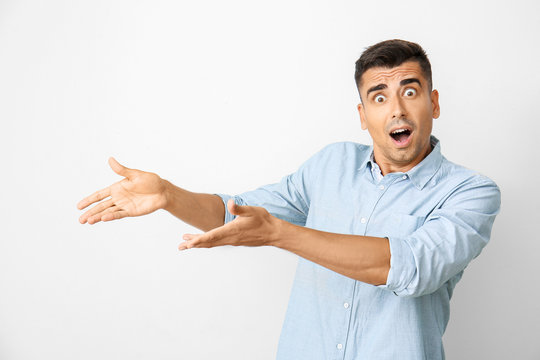 Shocked young man on light background