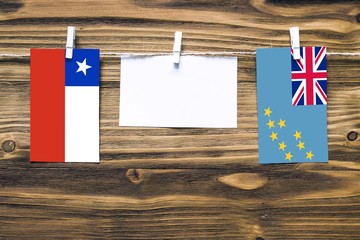 Hanging flags of Chile and Tuvalu attached to rope with clothes pins with copy space on white note...