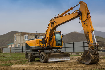 Yellow excavator at the construction of a cottage