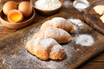Baked croissants with sugar powder on wooden board