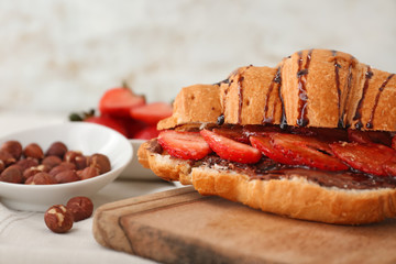 Tasty croissant with chocolate and strawberry on table, closeup