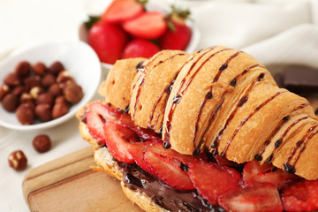 Tasty croissant with chocolate and strawberry on table, closeup
