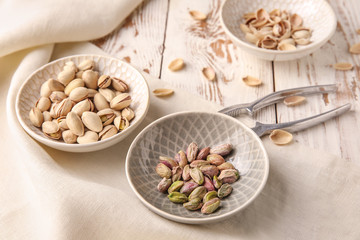Tasty pistachio nuts with nutcracker on table