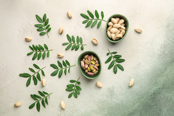 Fototapeta na wymiar Bowls with tasty pistachio nuts on light background