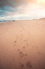 Beautiful seascape, a beach at sunset with footprint, close focus on print, and sunflare, exceptional tonality of color,warm and cyan