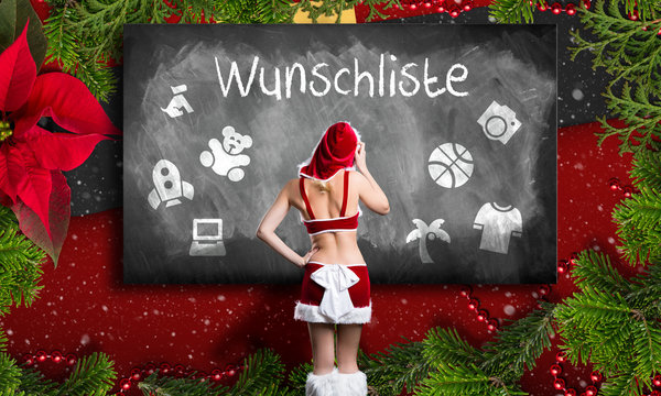 attractive blonde miss santa in front of a blackboard with a wishlist