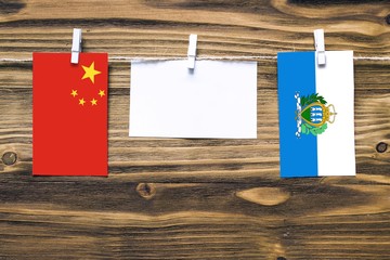 Hanging flags of China and San Marino attached to rope with clothes pins with copy space on white...
