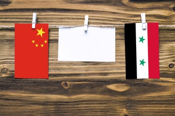 Hanging flags of China and Syria attached to rope with clothes pins with copy space on white note...