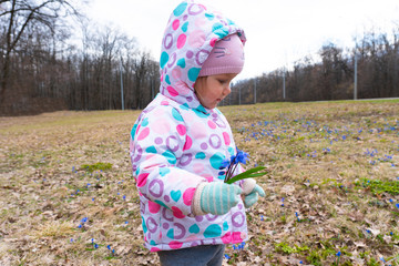 Little girl with spring snowdrop flowers in hand