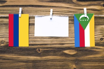 Hanging flags of Colombia and Comoros attached to rope with clothes pins with copy space on white...