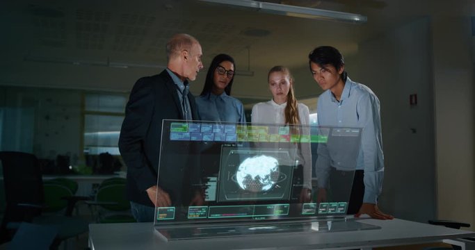 A group of designer are using a futuristic sophisticated technology screen with augmented reality holograms for a new worldwide global project realization in an office.