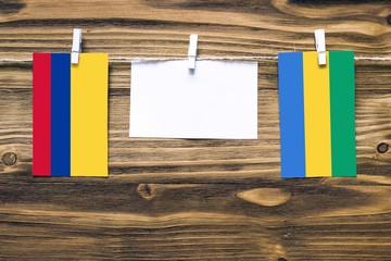 Hanging flags of Colombia and Gabon attached to rope with clothes pins with copy space on white...