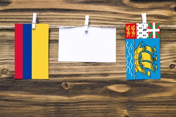 Hanging flags of Colombia and Saint Pierre And Miquelon attached to rope with clothes pins with...