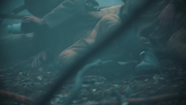 Wounded soldiers crawl on the ground in the foggy forest
