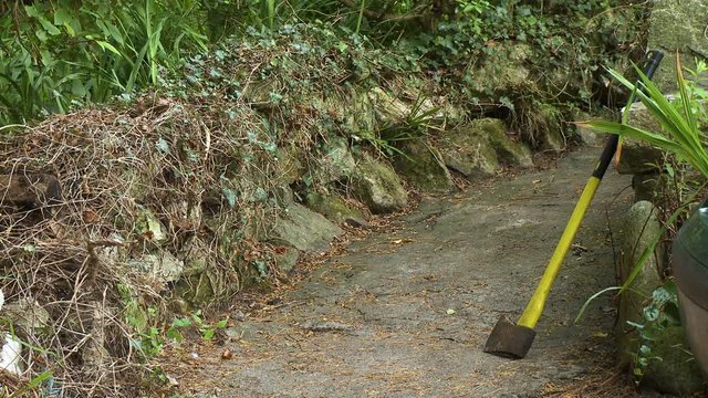 Steady, medium wide shot of an axe resting on a stone wall.