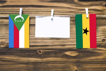 Hanging flags of Comoros and Ghana attached to rope with clothes pins with copy space on white note...