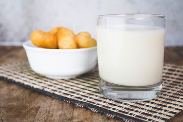 Soy milk in a glass and cup of fried cassava flour Resting on a brown wooden table