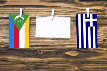 Hanging flags of Comoros and Greece attached to rope with clothes pins with copy space on white...
