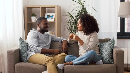 communication, relationships and people concept - happy couple sitting on sofa and talking at home - Powered by Adobe