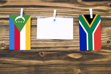Hanging flags of Comoros and South Africa attached to rope with clothes pins with copy space on...