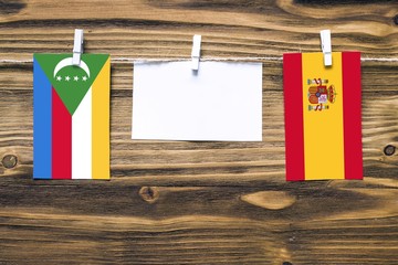 Hanging flags of Comoros and Spain attached to rope with clothes pins with copy space on white note...