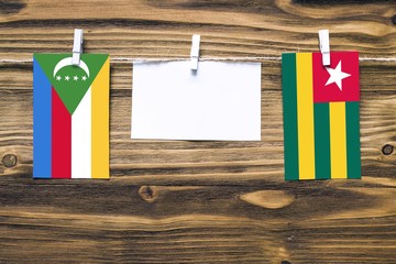 Hanging flags of Comoros and Togo attached to rope with clothes pins with copy space on white note...