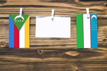 Hanging flags of Comoros and Uzbekistan attached to rope with clothes pins with copy space on white...