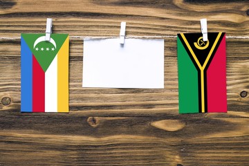 Hanging flags of Comoros and Vanuatu attached to rope with clothes pins with copy space on white...