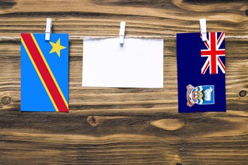 Hanging flags of Congo and Falkland Islands attached to rope with clothes pins with copy space on...