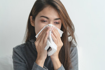 close up young girl using tissue paper stop runny nose symptom on the bed at home.