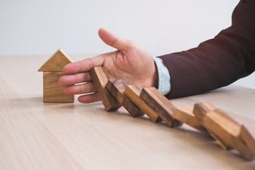 Protection finance from domino effect concept. Hands stop domino effect before destroy home.
