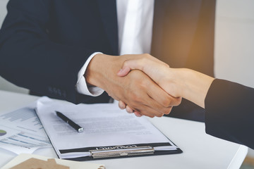 Two businessmen shaking hands after deal contract to mortgage real estate.