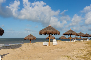 Straw kiosks on a beach in Brazil on a bright sunny day with blue skies