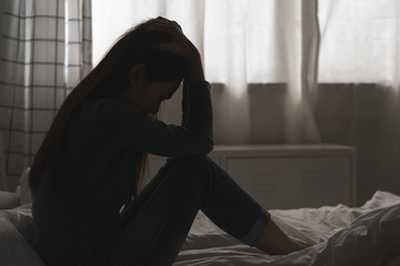 Suffer from depression , mental health problem. asian young woman sitting on the bed feeling depressed.