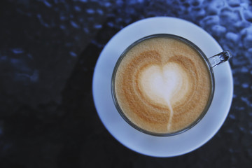 Coffee latte on glass table. Photo made in dark key.