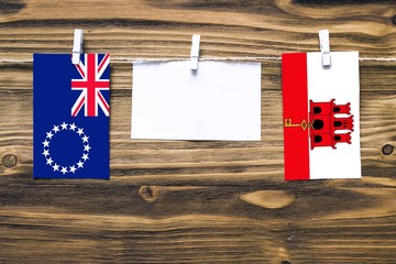 Hanging flags of Cook Islands and Gibraltar attached to rope with clothes pins with copy space on...
