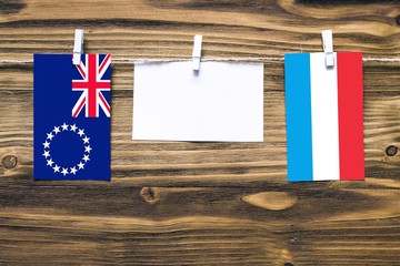 Hanging flags of Cook Islands and Luxembourg attached to rope with clothes pins with copy space on...