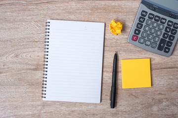 blank note with pen and calculator on wooden table background. marketing, financial concept