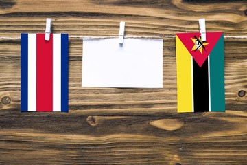 Hanging flags of Costa Rica and Mozambique attached to rope with clothes pins with copy space on...