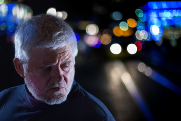 It's night in a city. A man looks suspiciously into the darkness. Concept: dangerous city