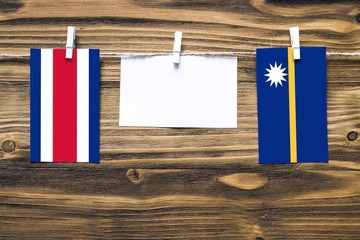 Hanging flags of Costa Rica and Nauru attached to rope with clothes pins with copy space on white note paper on wooden background.Diplomatic relations between countries.