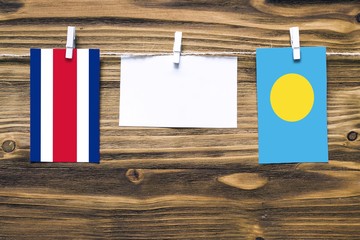 Hanging flags of Costa Rica and Palau attached to rope with clothes pins with copy space on white...