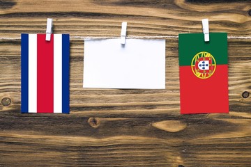 Hanging flags of Costa Rica and Portugal attached to rope with clothes pins with copy space on...