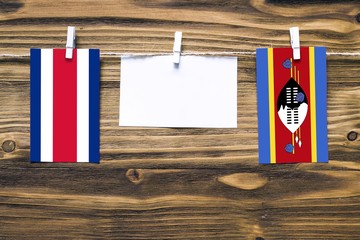 Hanging flags of Costa Rica and Swaziland attached to rope with clothes pins with copy space on...
