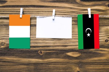 Hanging flags of Cote D'Ivoire and Libya attached to rope with clothes pins with copy space on...