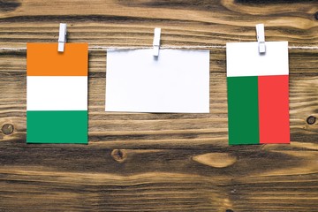 Hanging flags of Cote D'Ivoire and Madagascar attached to rope with clothes pins with copy space on...