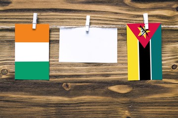 Hanging flags of Cote D'Ivoire and Mozambique attached to rope with clothes pins with copy space on...