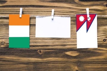 Hanging flags of Cote D'Ivoire and Nepal attached to rope with clothes pins with copy space on...